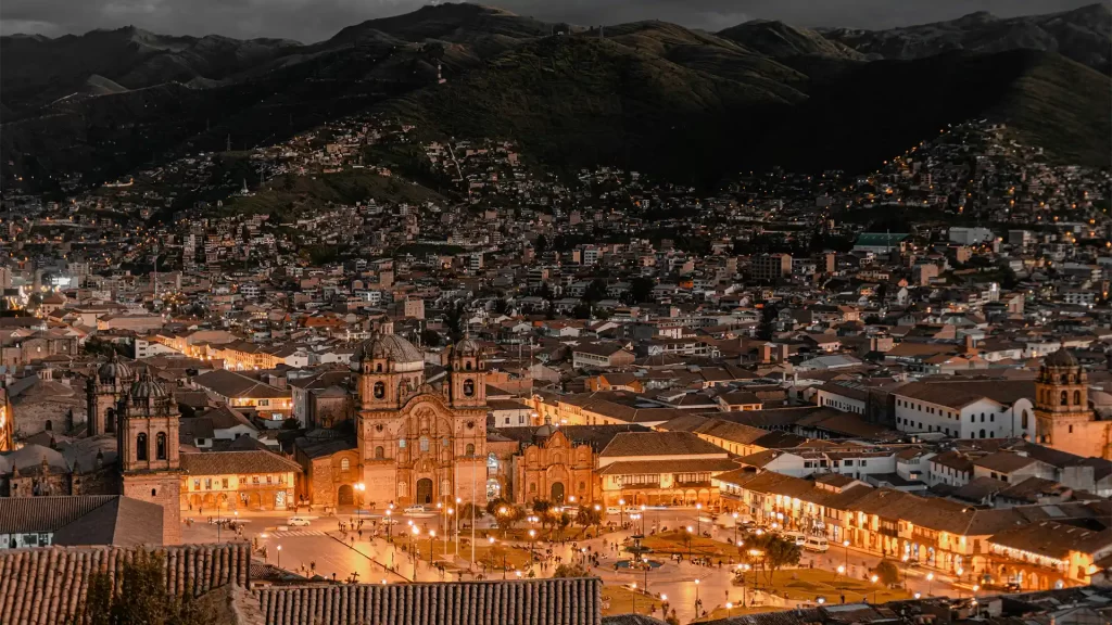 Plaza de Armas de Cusco con la Catedral iluminada y turistas caminando.