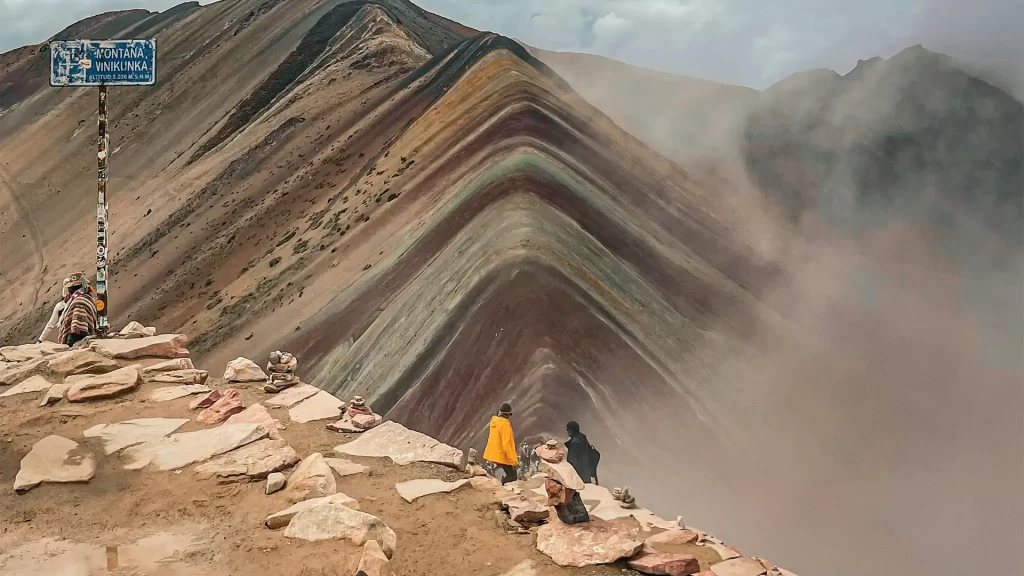Turistas paseando por las montañas con vista a las montañas de colores en el Valle Rojo.