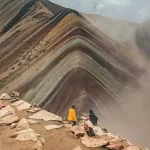 Turistas paseando por las montañas con vista a las montañas de colores en el Valle Rojo.