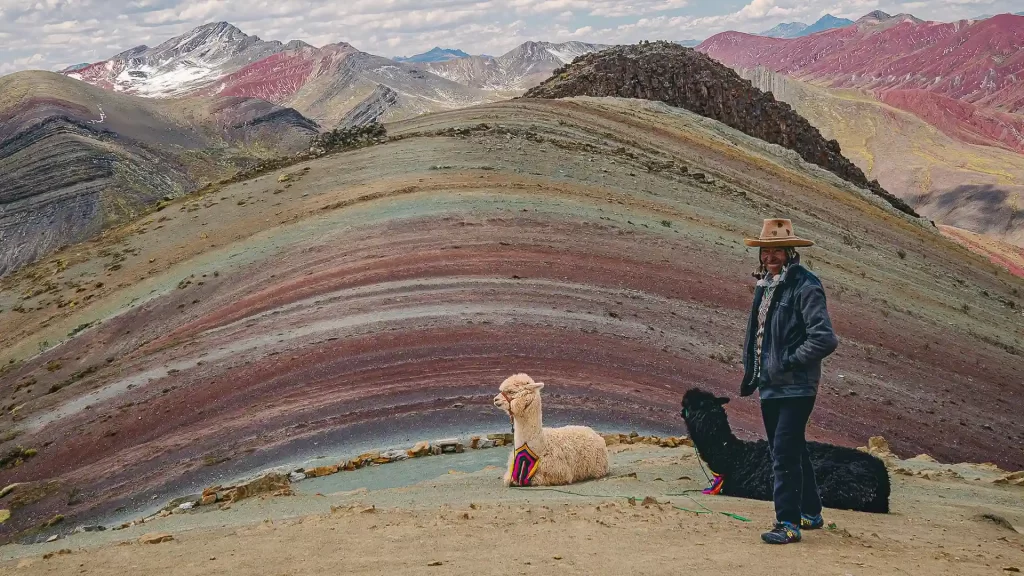 Tour en cuatrimoto hacia la Montaña de Colores con llamas en el paisaje andino.